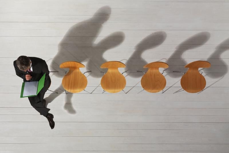 Overhead image of person sitting in a line of empty chairs