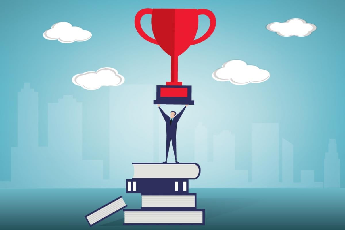 Person holding a trophy on a stack of books