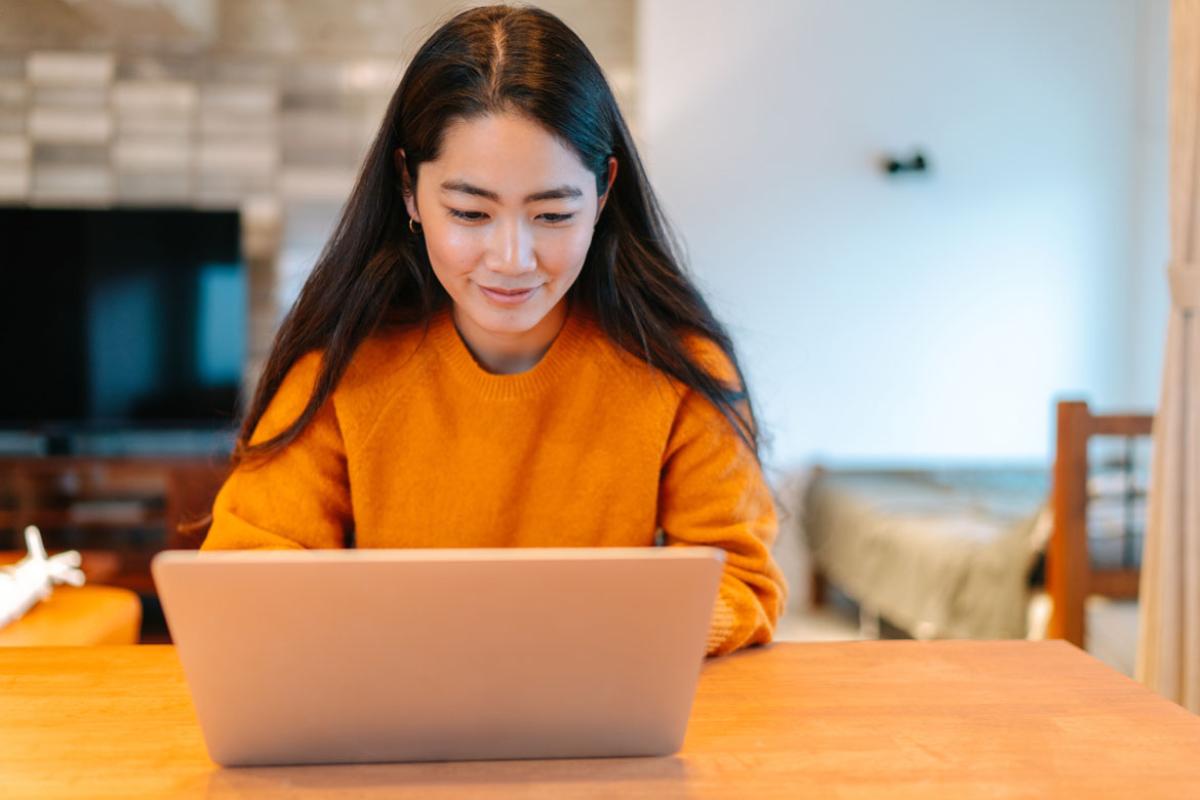 Woman smiling, working at her lap top in her living room.