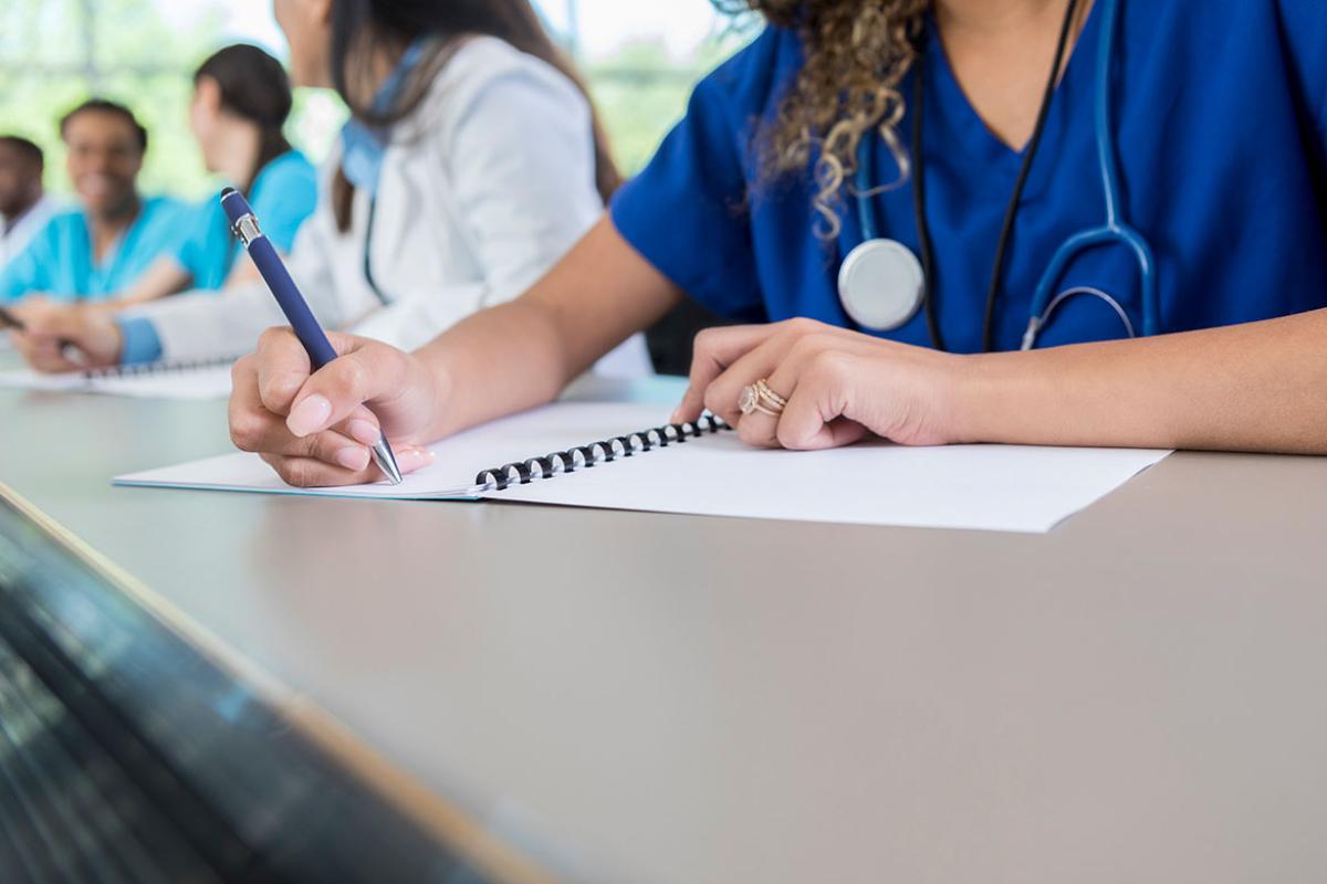 Health care professional writing in a notebook