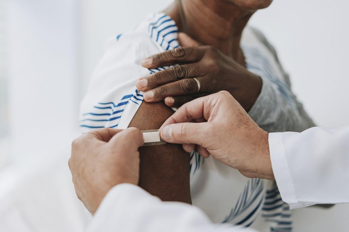 Health care worked applying bandage to patient's upper arm