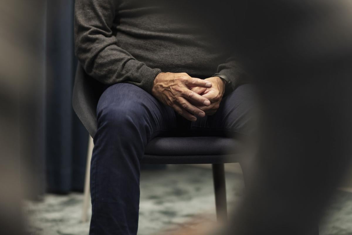 Seated person with hands clasped