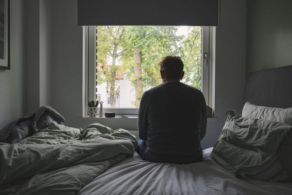 Man sitting on his bed looking out of the window
