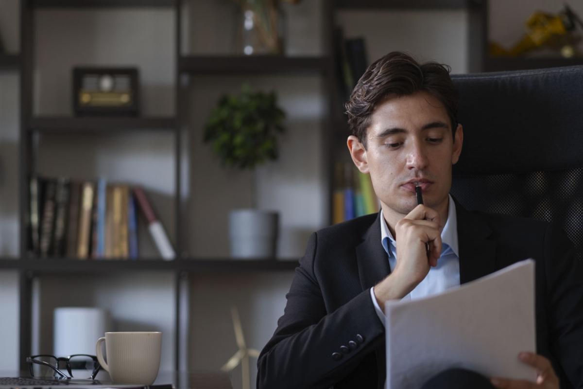 Businessperson in suit carefully reading official documents in office