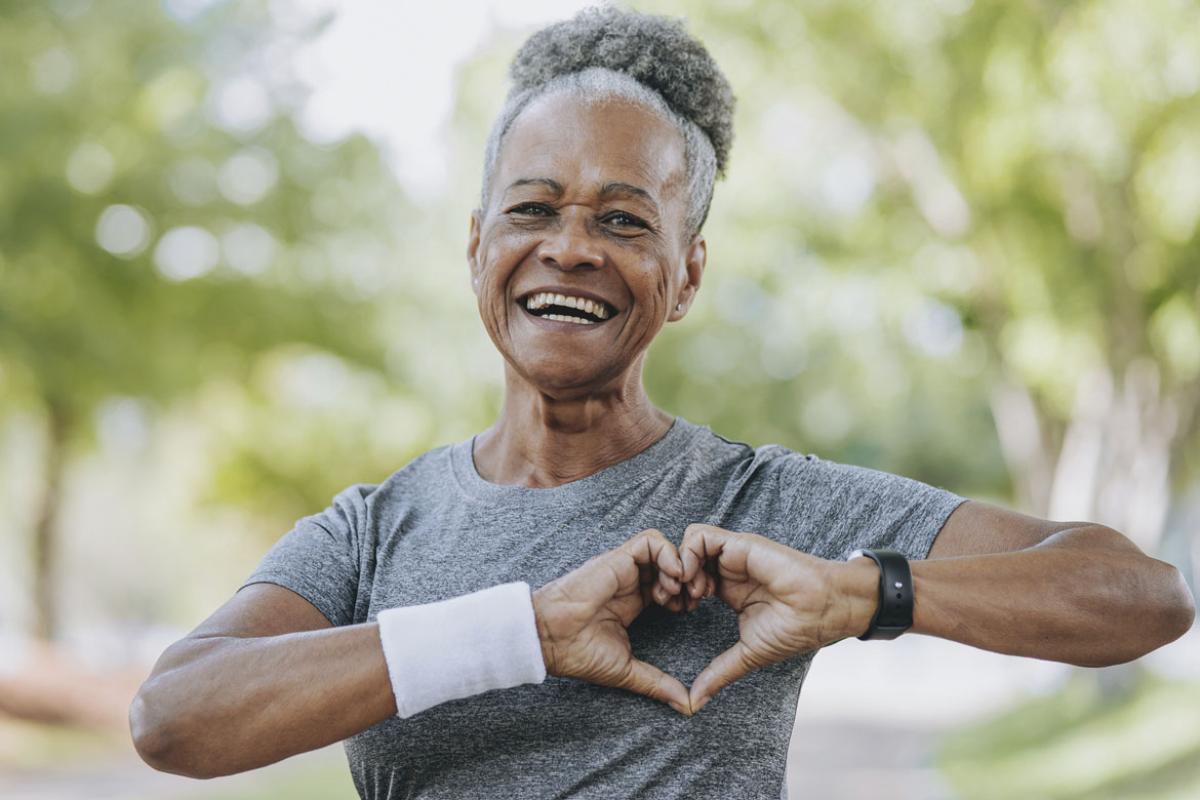 Smiling person makes a heart symbol with hands