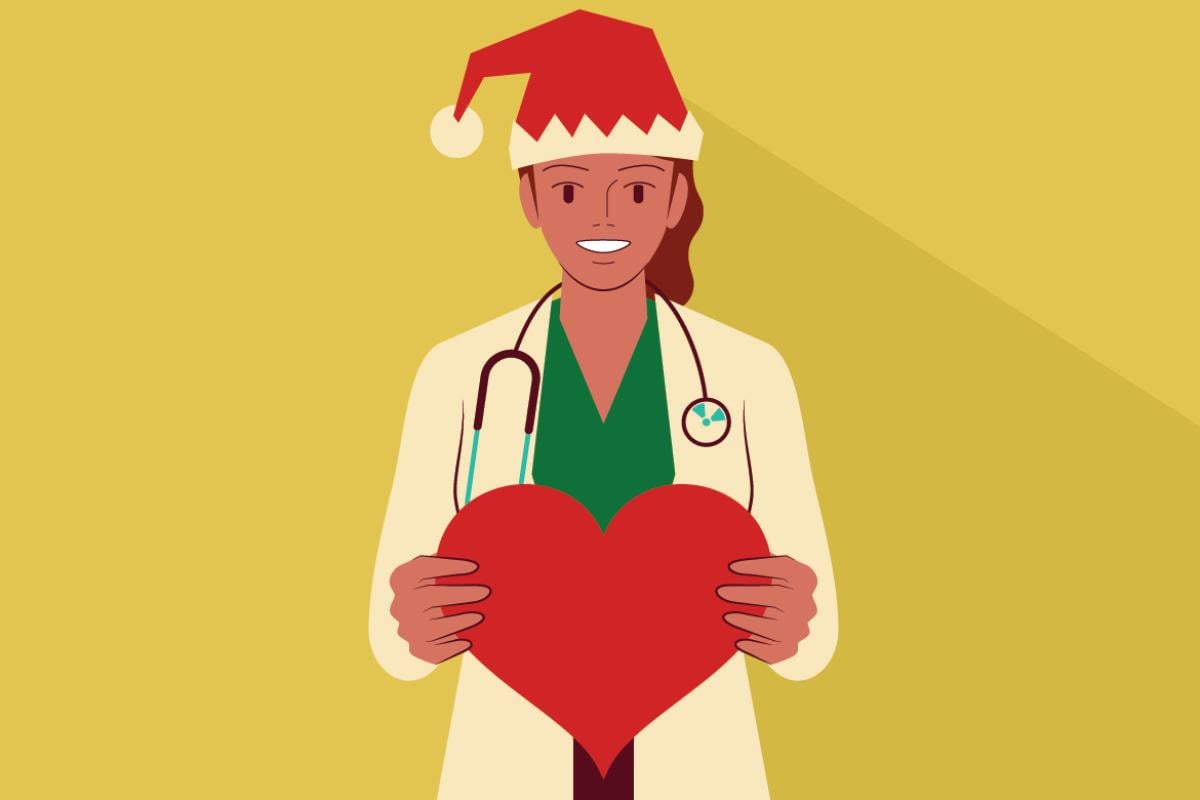 Smiling doctor wearing a Santa hat holds a cut-out heart