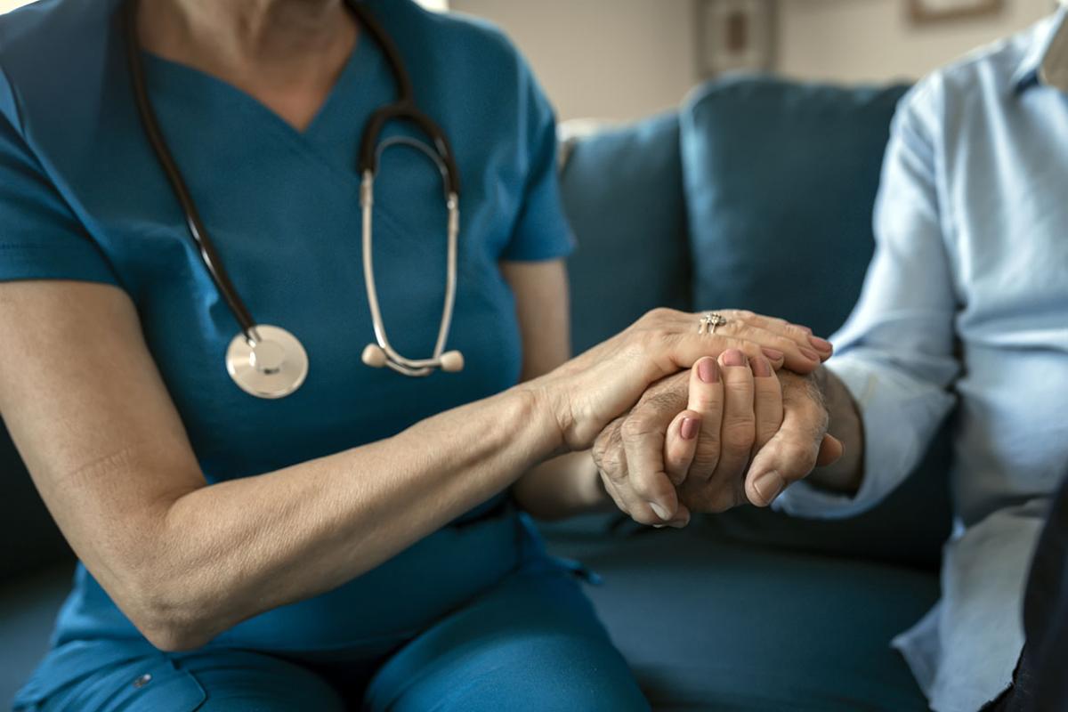 Health care worker holds hands with patient
