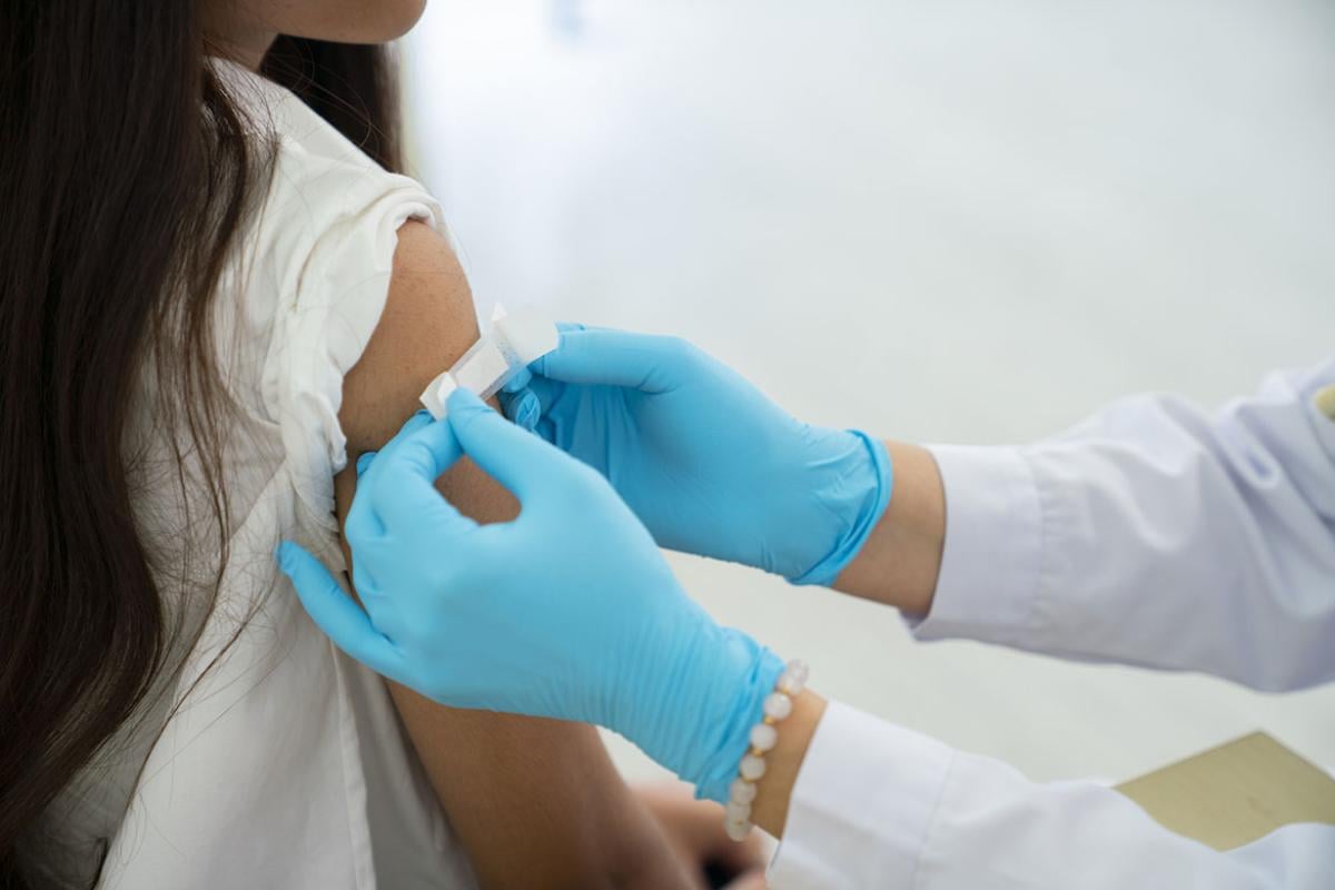 Doctor applies bandage to patient's arm following an immunization