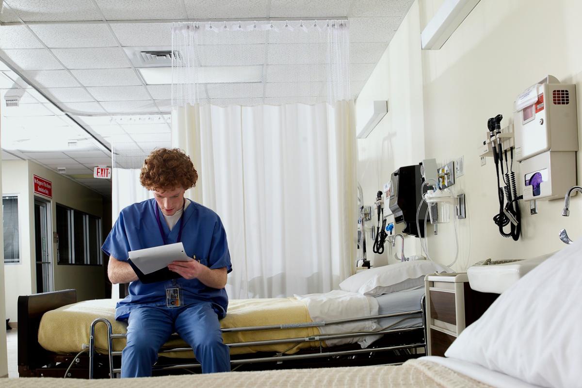 A resident studies his notes in an empty hospital room. 