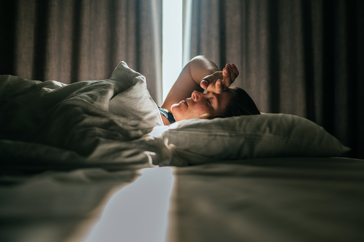 Person in bed, hand over forehead